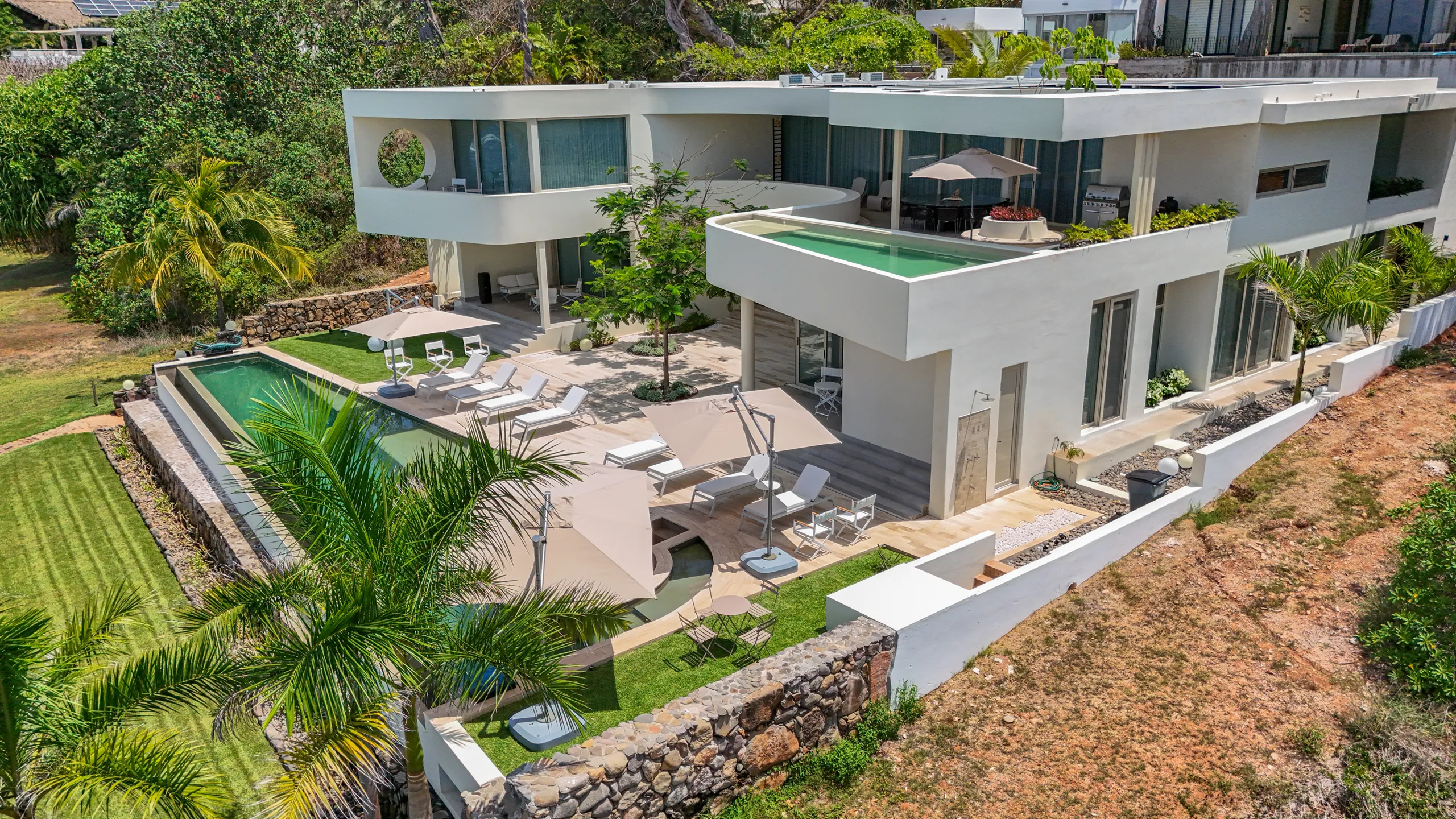 An elevated architectural perspective showcasing the residence’s layered outdoor spaces, rooftop terrace, and direct oceanfront positioning.