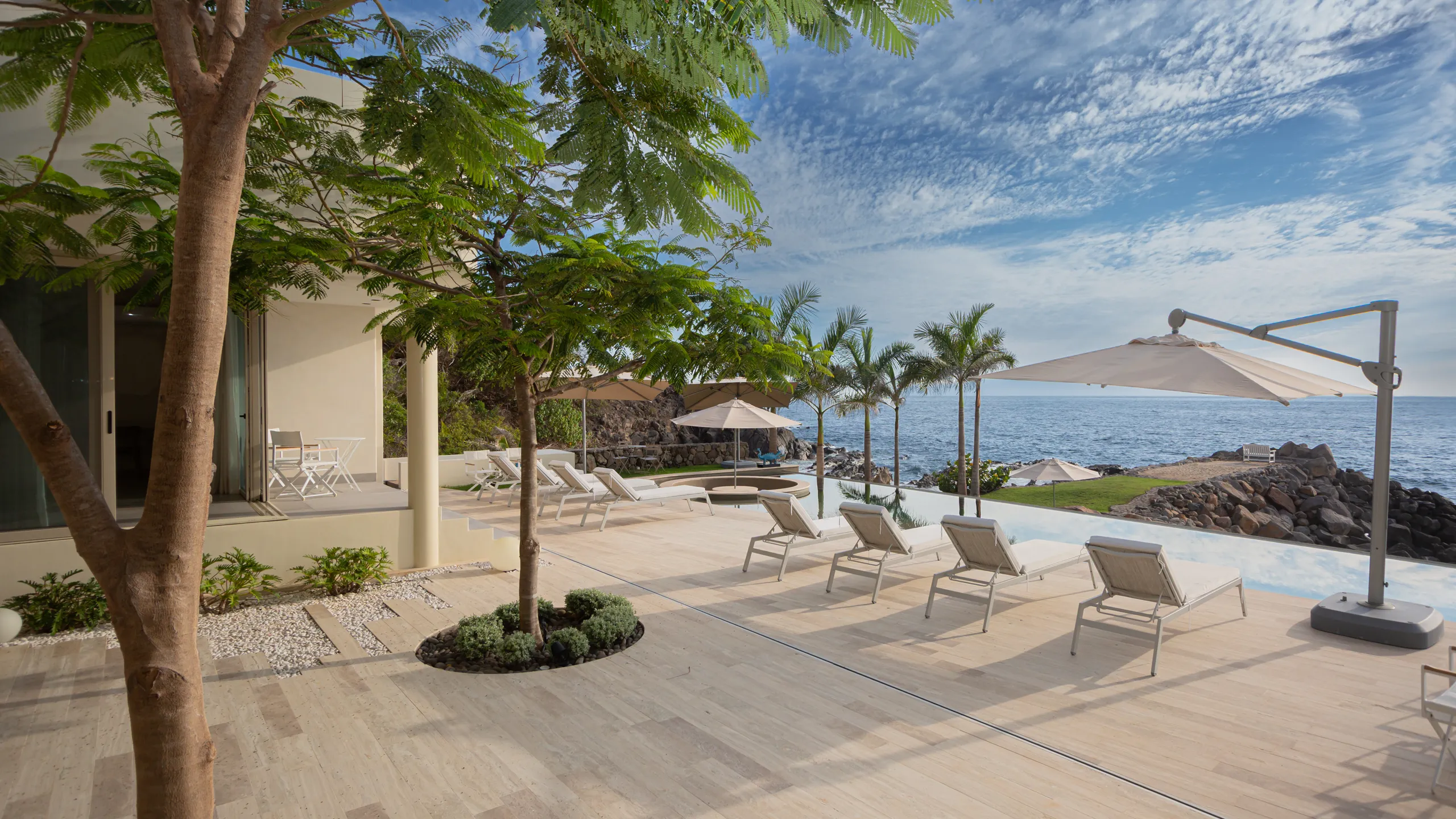 Expansive outdoor living areas seamlessly connected to the infinity pool and the Pacific shoreline beyond.