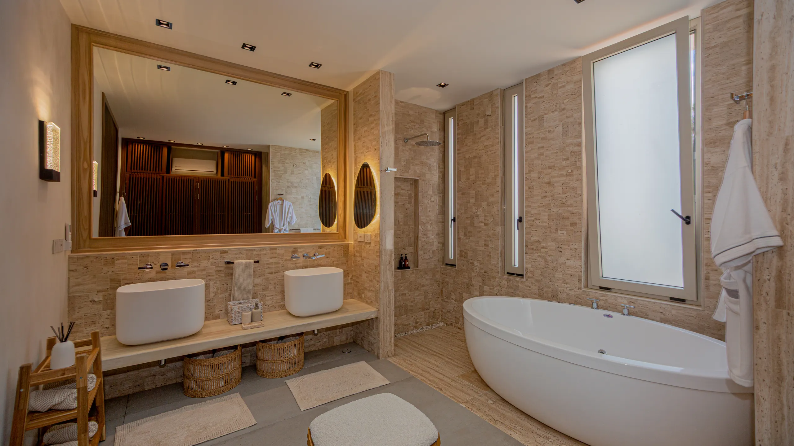 Spa-inspired primary bathroom finished with natural stone textures, warm lighting, and a refined contemporary palette.