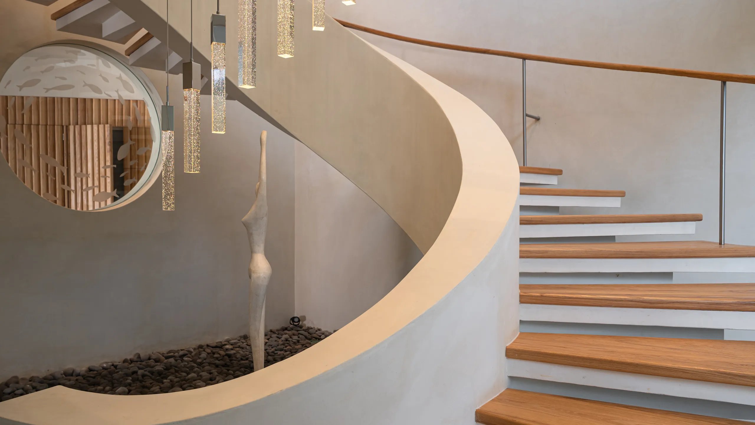 A sculptural staircase serves as a central architectural feature, blending contemporary design with organic forms and warm materials.