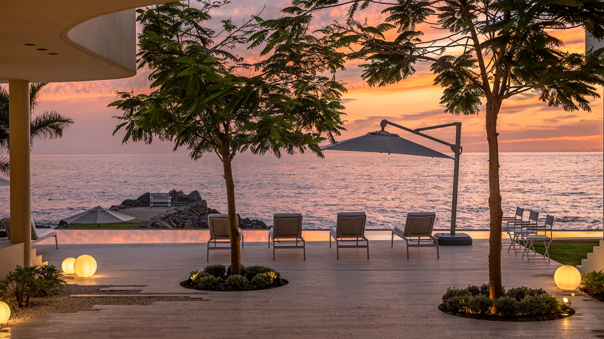 Evening oceanfront atmosphere designed for quiet moments, open-air living, and panoramic sunset views over the Pacific.