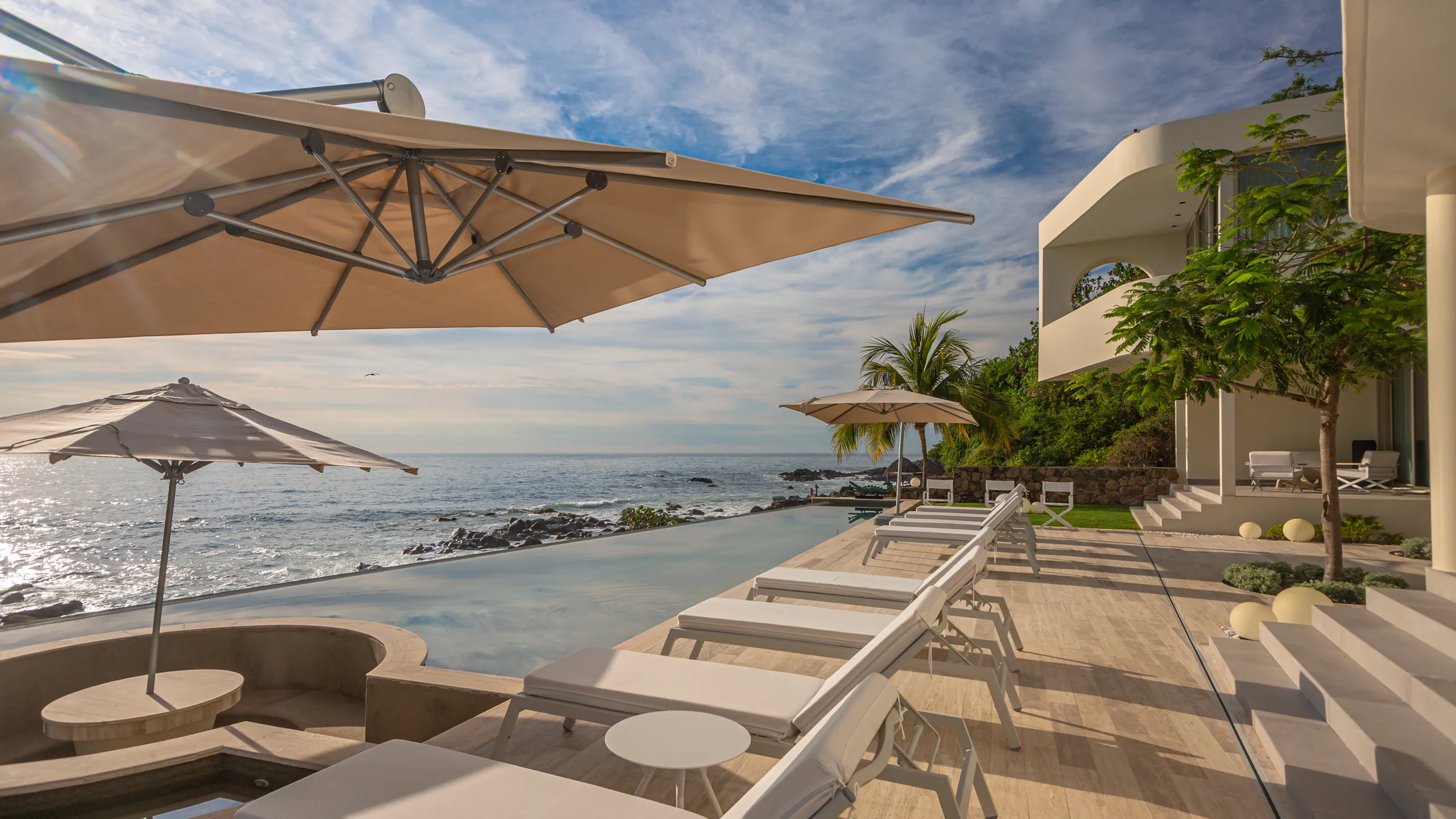 Private oceanfront lounge spaces positioned along the edge of the coastline, creating a refined indoor-outdoor experience.